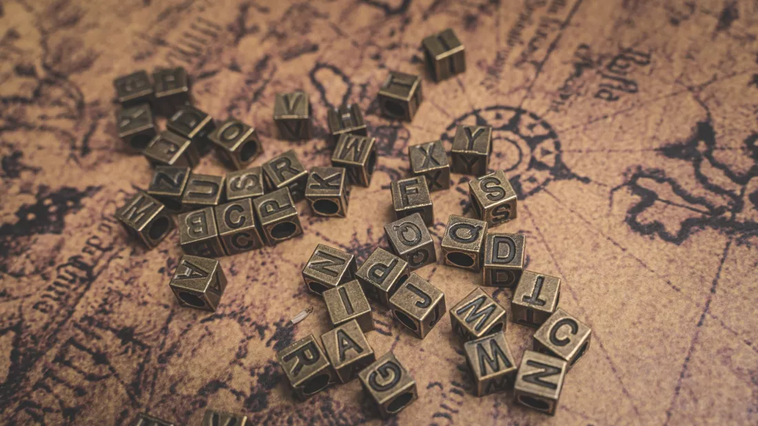Bronze alphabet letters on an old world map