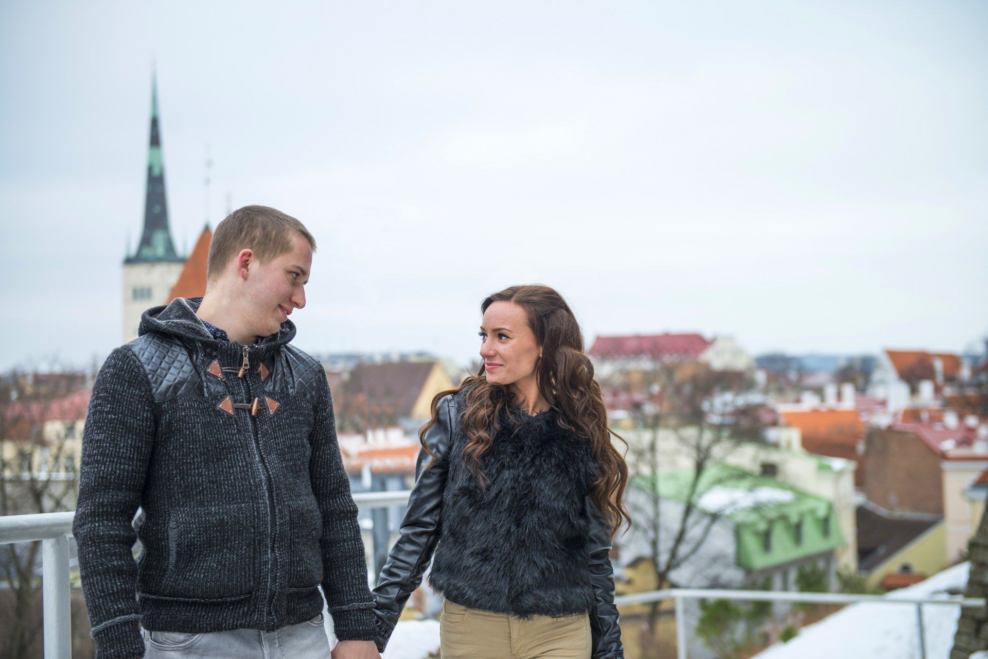 Young couple holding hands against the rooftops of Tallinn Old Town